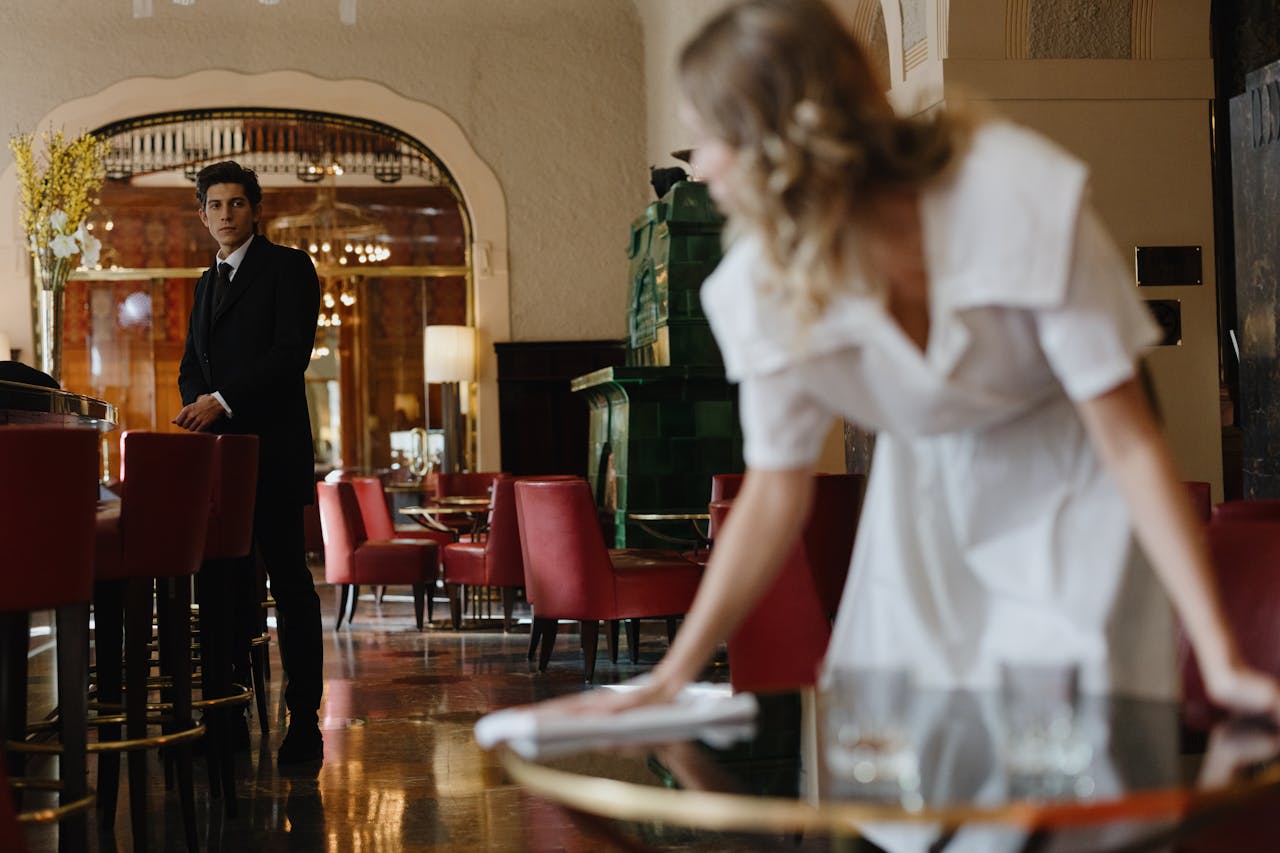 who-we-are A waiter and waitress in a stylish restaurant setting, focusing on service and elegance.